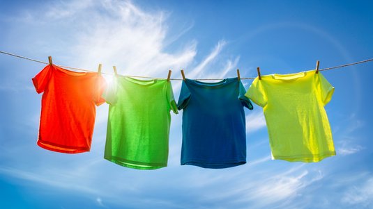 Vier T-Shirts hängen an einer Wäscheleine