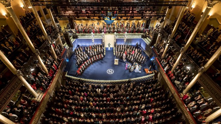 Verleihung der Nobelpreise in Stockholm | Bildquelle: Alexander Mahmoud/Nobel Media AB Das Bild zeigt die Preisverleihung von oben. Man sieht mehrere Stuhlreihen, mit Blick auf eine Bühne.