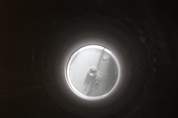 Der Blick von oben auf die Fragmentationsbombe durch das Edelstahlrohr hindurch zeigt die staubige Öffnung des Druckbehälters nach einer Ascheexplosion. 

