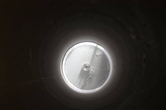 Ein Blick von oben auf die Fragmentationsbombe Der Blick von oben auf die Fragmentationsbombe durch das Edelstahlrohr hindurch zeigt die staubige Öffnung des Druckbehälters nach einer Ascheexplosion.