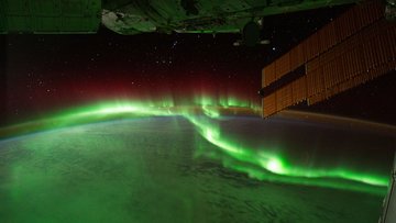 Das Bild zeigt eine Aufnahme der Nordlichter aus dem Weltraum. Die Nordlichter befinden sich hell leuchtend über der dunklen Erde.