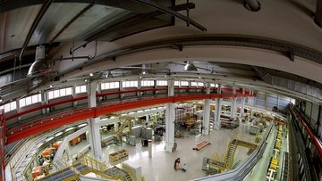 Ovaler Aufbau einer großen, langgezogenen Maschine in einer Halle.