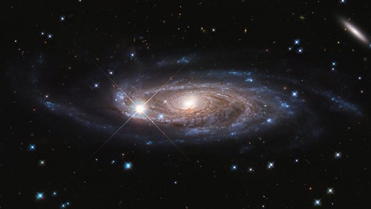 Aufnahme einer Spiralgalaxie: Ein heller, gelblich-weißer Kern wird von bläulichen Spiralarmen umhüllt. 