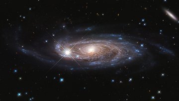 Aufnahme einer Spiralgalaxie: Ein heller, gelblich-weißer Kern wird von bläulichen Spiralarmen umhüllt. 