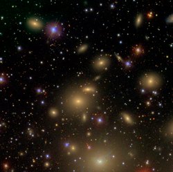Aufnahme des Perseus-Galaxienhaufens – die einzelnen Galaxien heben sich in Form vieler bunter Lichtflecken vor dem schwarzen Hintergrund des Weltalls ab.
