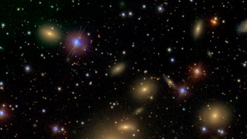Aufnahme des Perseus-Galaxienhaufens – die einzelnen Galaxien heben sich in Form vieler bunter Lichtflecken vor dem schwarzen Hintergrund des Weltalls ab.