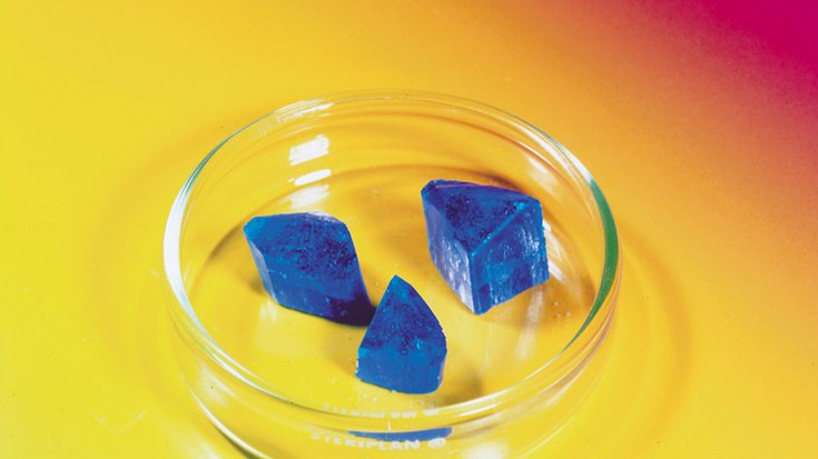 Drei blaue Kristalle in eienr Petrischale.