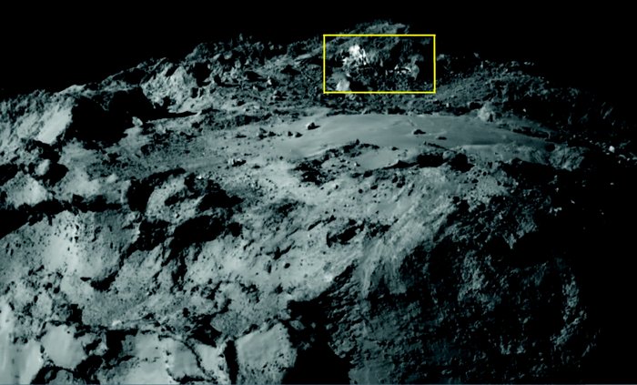 Eis auf Kometen entdeckt Ausschnitt der Oberfläche des Kometen Tschurjumow-Gerassimenko. Oberhalb einer flachen Ebene sind helle Flecken zu erkennen.