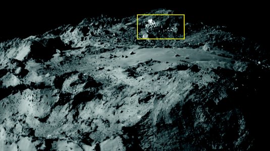 Ausschnitt der Oberfläche des Kometen Tschurjumow-Gerassimenko. Oberhalb einer flachen Ebene sind helle Flecken zu erkennen.