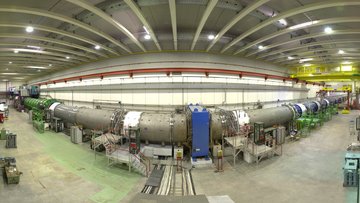In einer großen Halle steht eine lange Röhre. Dabei handelt es sich um einen 120 Meter langen Vakuumtank, in dem die Kaonen zerfallen. Detektoren im Inneren des Tanks vermessen die Zerfallsprodukte. 