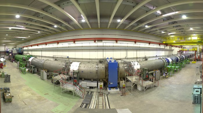 In einer großen Halle steht eine lange Röhre. Dabei handelt es sich um einen 120 Meter langen Vakuumtank, in dem die Kaonen zerfallen. Detektoren im Inneren des Tanks vermessen die Zerfallsprodukte.