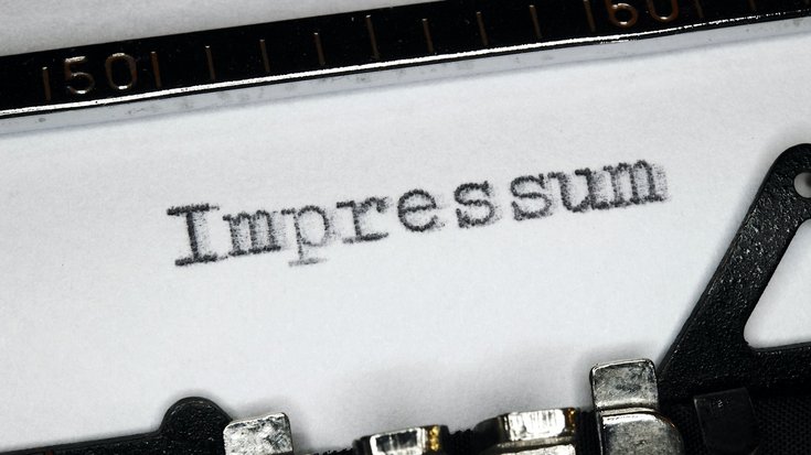 Das Foto zeigt eine alte Schreibmaschine. Auf ein weißes Blatt Papier wurde das Wort Impressum geschrieben.