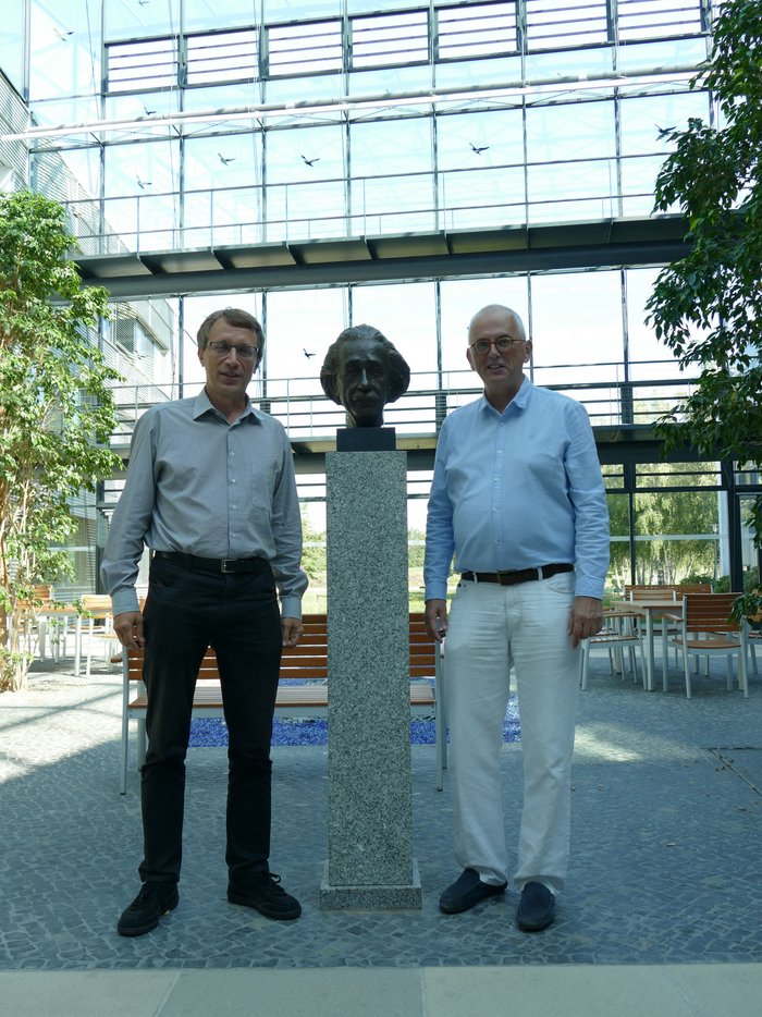 Krzysztof Meissner und Hermann Nicolai Das Bild zeigt die beiden Forscher Krzysztof Meissner und Hermann Nicolai. Zwischen ihnen steht eine Skulptur von Albert Einstein.