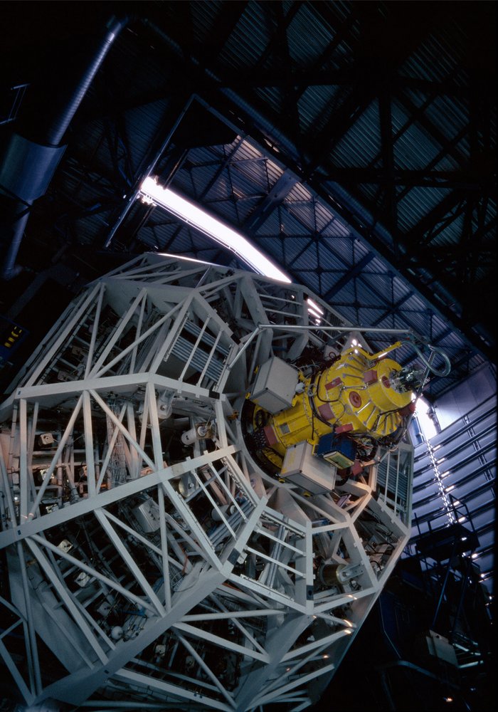 Das FORS1-Instrument in gelb ragt aus der Mitte des runden Hauptspiegels heraus, gesehen von dessen Rückseite.