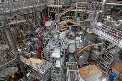 Wendelstein 7-X wurde vom Max-Planck-Institut für Plasmaphysik an seiner Teilstelle in Greifswald gebaut. Diese Aufnahme zeigt eine Ansicht der Torushalle mit der bereits geschlossenen Experimentieranlage. Das Innere des Torus und die Magnetspulen sind hier bereits nicht mehr zu sehen, sondern von einem weiteren Torus umgeben.
