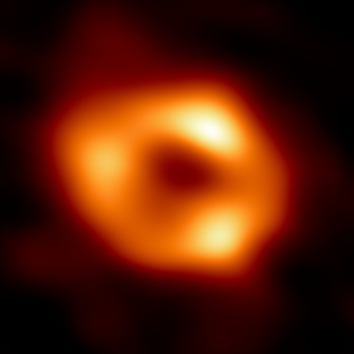 Erste Aufnahme von Sagittarius A* Vor einem dunklen Hintergrund zeichnet sich ein verschwommener, hell leuchtender Ring ab.