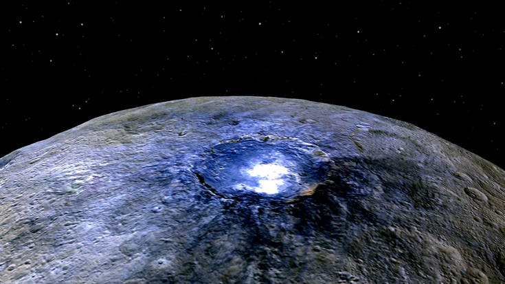 Krater mit hellen Flecken auf felsigem Himmelskörper. Bei den hellen Flecken handelt es sich um Salzablagerungen.