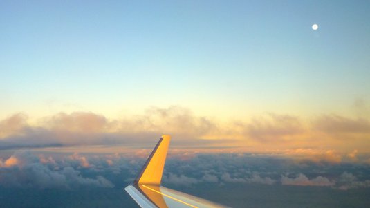 Flugzeugflügel vor Wolken im Sonnenschein