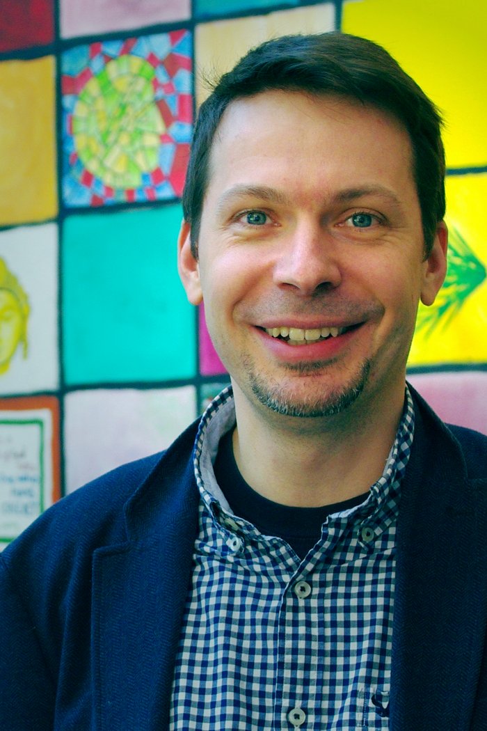Michael Wilczek Das Bild zeigt den Forscher Michael Wilczek vor bunten Fliesen.