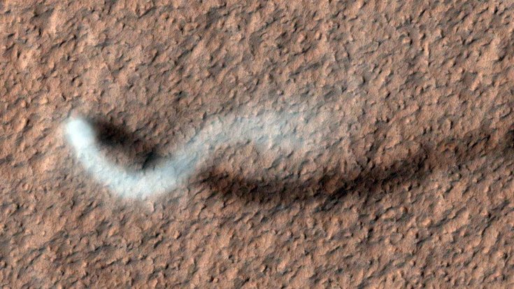 Ein wolkenartiges Gebilde zieht schlängelnd über die Marsoberfläche