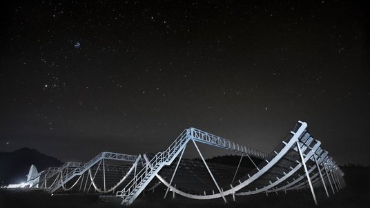 Mehrere große Metallbögen, über die Leitergänge verlaufen, unter einem Sternenhimmel