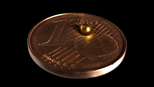 Fotomontage: Winzige Goldkugel liegt auf einem 1-Cent-Stück und drückt eine Delle hinein 