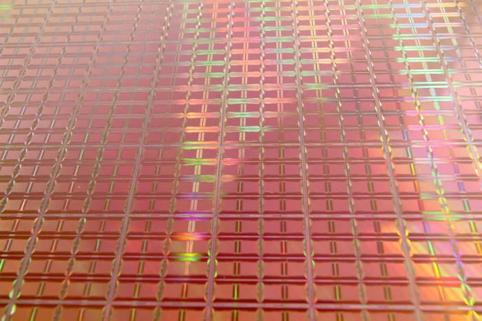Chips auf einem Siliziumwafer Ein engmaschiges Gitter, in dem sich Licht großflächig reflektiert.