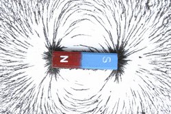 Stabmagnet, der Nordpol ist rot, der Südpol blau eingefärbt. Eisenspäne um den Magneten ordnen sich entlang der Feldlinien an, die von einem Pol zum anderen verlaufen.