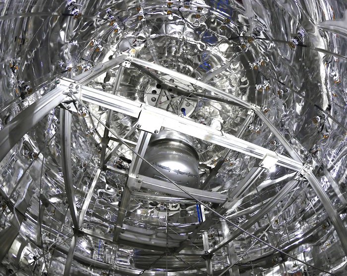 Detektor im Wassertank Blick in einen zylindrischen Raum, der innen mit Folie ausgekleidet ist und in dem ein Metallgestellt steht.