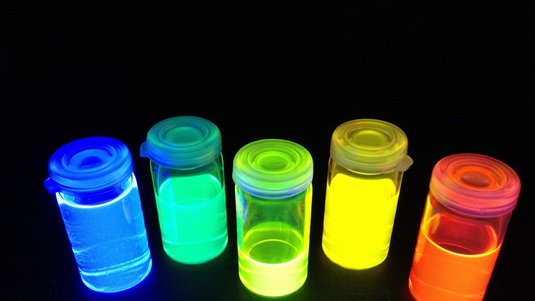 Die Flaschen mit einem farbig leuchtenden Inhalt beinhalten eine neue Generation farbiger Emittermoleküle, die in Zukunf vielleicht in OLEDs eingesetzt werden können.