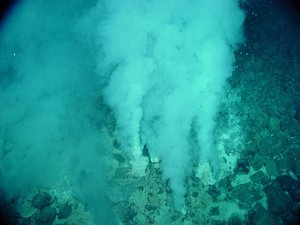 Unter Wasser steigt aus einem steinigen Untergrund Rauch auf