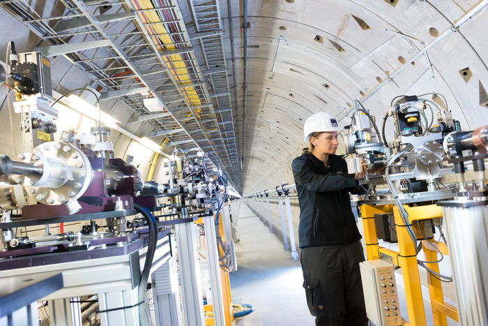 Experiment am European XFEL Das Bild zeigt eine Forscherin, die an verschiedenen Geräten in einem unterirdischen Tunnel arbeitet.