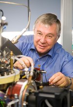 Ein Mann mit Brille blickt über einen technischen Aufbau in die Kamera.