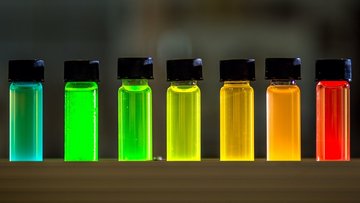 Auf dem Foto sind sieben kleine Glasfläschchen zu sehen, gefüllt mit farbigen Flüssigkeiten.