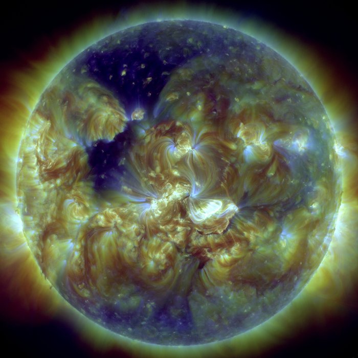 Sonnenscheibe in dunkler Farbe vor noch dunklerem Nachthimmel ist von hellen, leuchtenden nebelartigen Schleiern umgeben – den Aktivitätsregionen.