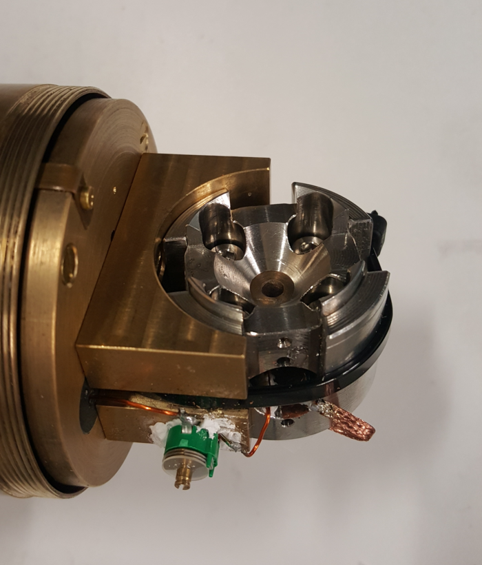 Probenhalter für die NMR-Spektroskopie Das Bild zeigt eine Metallhalterung mit einigen Kabelverbindungen.