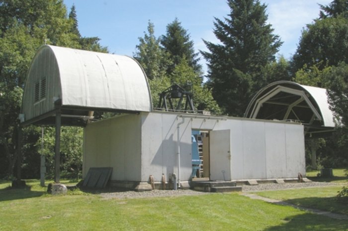 Gebäude mit Tonnendach, das in zwei Hälften nach links und rechts auf Schienen laufend geöffnet ist.