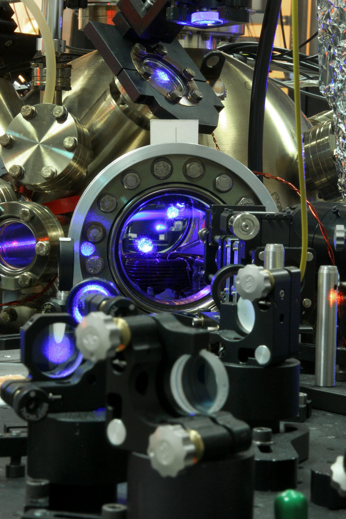 Optische Strontium-Atomuhr der PTB. Das Bild zeigt einen komplexen Aufbau aus Metal, in dessen Inneren ein violettes Licht leuchtet.