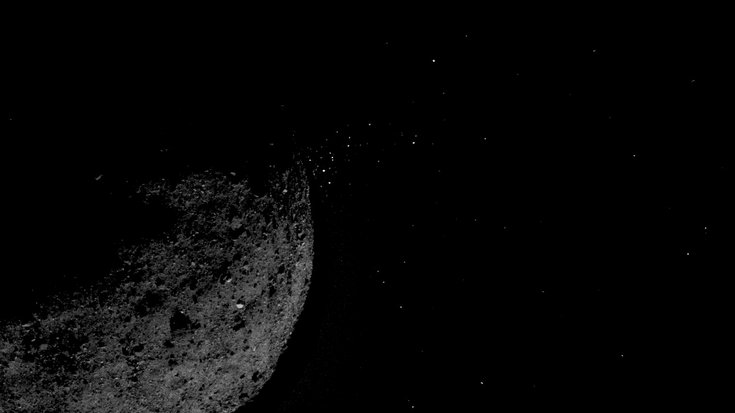 Beleuchtete Seite eines Asteroiden, um den kleine Gesteinsteilchen schweben