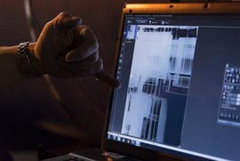 Eine Hand deutet auf einen Computerbildschirm. Auf diesem ist eine schwarz-weiße Aufnahme zu sehen, die technische Teile im Röntgenbild zeigt.