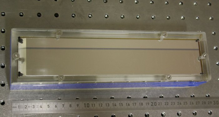 Röntgenspiegel für FLASH II Eine metallene Platte, eingefasst in Plastik. Darunter zum Größenvergleich ein Lineal: Die Platte ist etwa 28 Zentimeter lang und einige Zentimeter hoch.