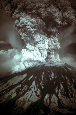 Schwarzweißfoto des Vulkans, aus dem Krater steigt eine dicke Wolke aus Staub und Gas auf.