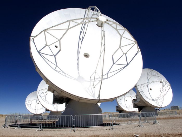 Eine der Radioantennen des ALMA-Observatoriums, die zwölf Meter Durchmesser hat und in der chilenischen Atacama-Wüste steht. Im Hintergrund sind weitere Antennen zu sehen.