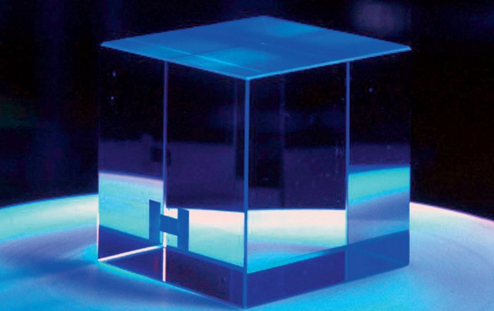 CRESST Saphir-Kristall Foto: Nahezu durchsichtiger, glas-ähnlicher Würfel mit vier Zentimetern Kantenlänge in blauem Licht.