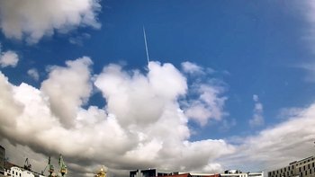 Durch einen blauen Himmel mit Wolken verläuft ein auffällig weißer Strich