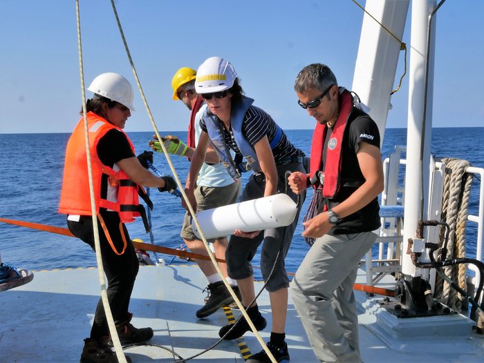 Arbeiter auf einem Forschungsschiff hält eine Leine in der Hand, an der die Sonde aus dem Wasser gezogen wird.
