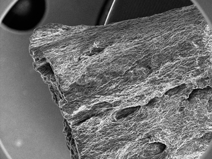 Elektronenmikroskopische Aufnahme des Sensormaterials Schwarz-Weiß-Bild einer rauhen Oberfläche eines uneben begrenzten Stücks Materie aus mehreren unregelmäßigen Schichten.