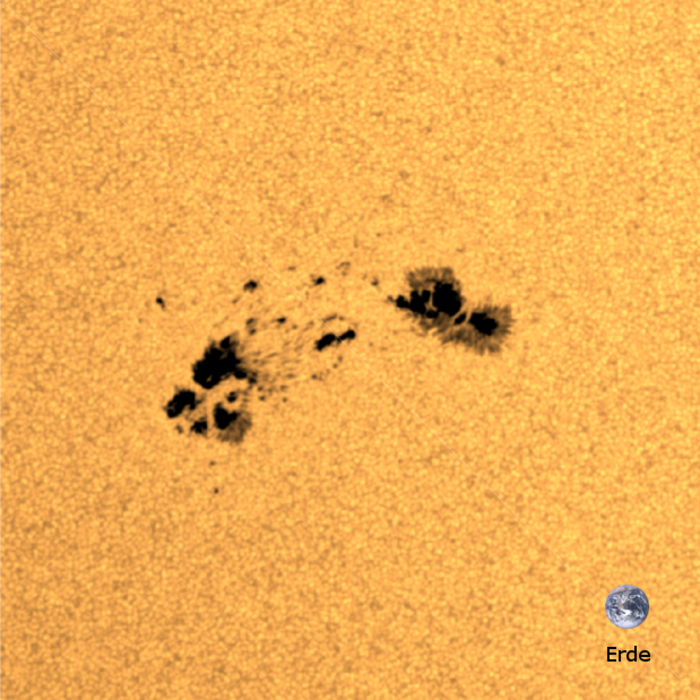 In der Nahaufnahme ist ein Sonnenfleck zu sehen, also eine dunklere Region auf der Sonnenoberfläche, die einige tausend Grad Celsius kühler ist als die umgebende Oberfläche. Rechts unten im Bild befindet sich die Erde maßstabsgetreu zum Größenvergleich.