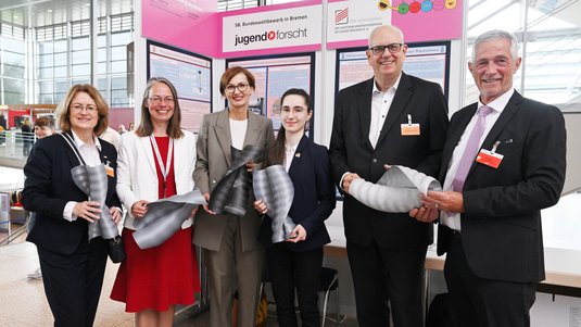 6 Personen stehen mit Exponaten vor einer Wand mit der Aufschrift jugend forscht