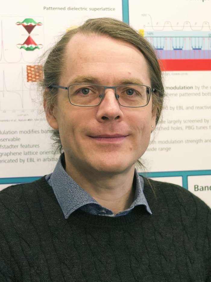 Jonathan Eroms Das Bild zeigt den Forscher vor einem Poster mit kleinen Abbildungen.